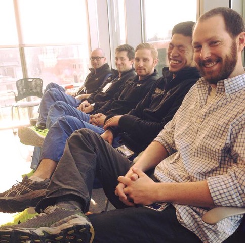 Five residents sitting cross-legged in a line and smiling