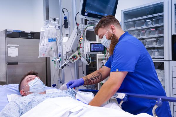 An emergency medicine resident trains serving a patient in the emergency department