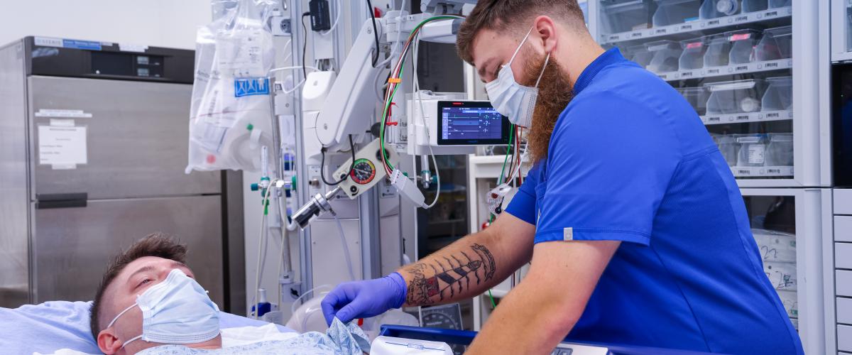 An emergency medicine resident trains serving a patient in the emergency department